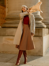 a lady wears a red knitted top with a beige lapel coat